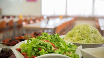 Un comedor con mesas dispuestas para comidas, incluyendo un plato de ensalada y un tazón de col rallada.
