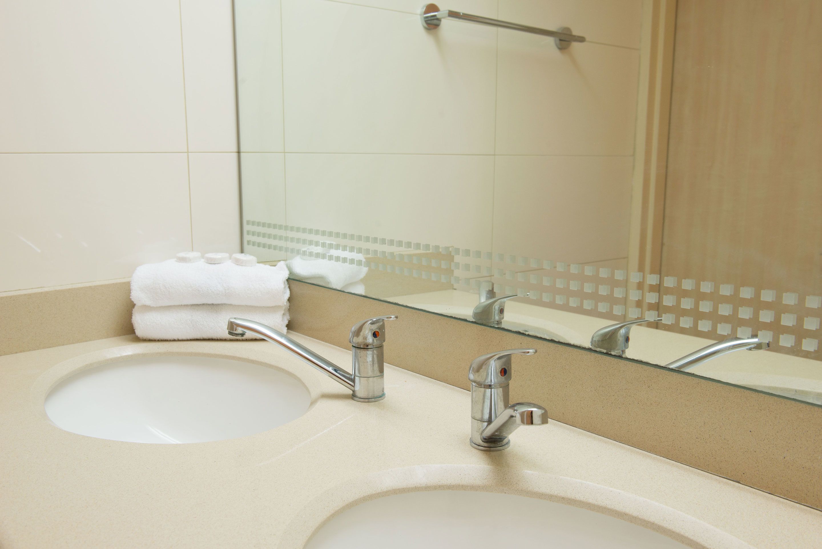 Un baño con dos lavamanos, un perchero para toallas y un espejo.