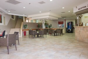 A reception area with a staircase, seating, and a vending machine.