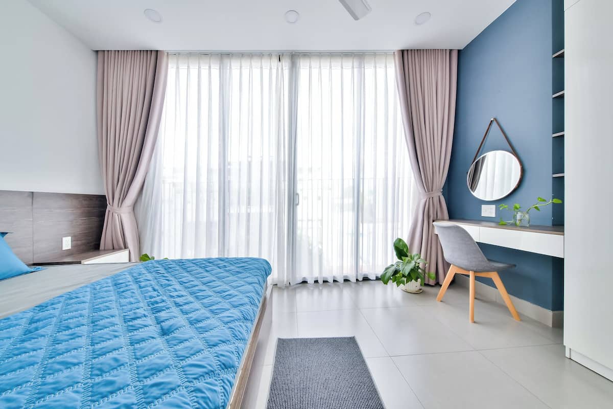 A modern bedroom with a large bed, a desk, and a chair.