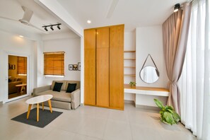 A modern living room with a sofa, a coffee table, a wooden wardrobe, a mirror, and a potted plant. - Proview house (Ho Chi Minh City)