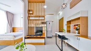 Moderni hotellihuone, jossa on sänky, televisio, ruokailutila ja pieni keittiönurkkaus.