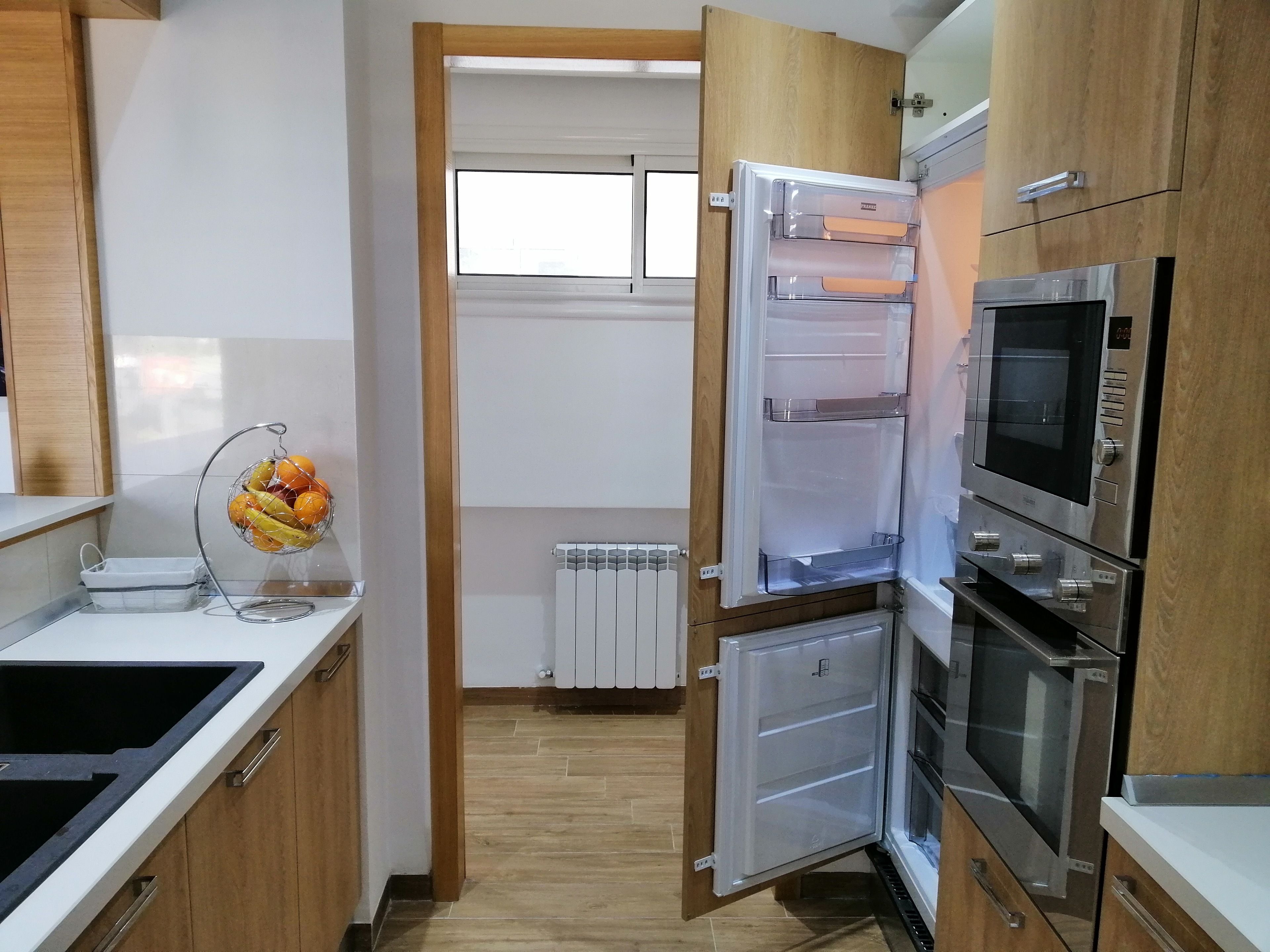 A modern kitchen with a built-in refrigerator, oven, and microwave.