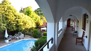 A pool area with lounge chairs and a covered seating area with a view of the pool. - Posada San Bras (Villa General Belgrano)