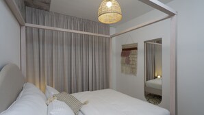 A bedroom with a bed, a hanging light fixture, a mirror, and a wall-mounted tapestry. - Mr. Yavos - By TLV2GO (Tel Aviv)