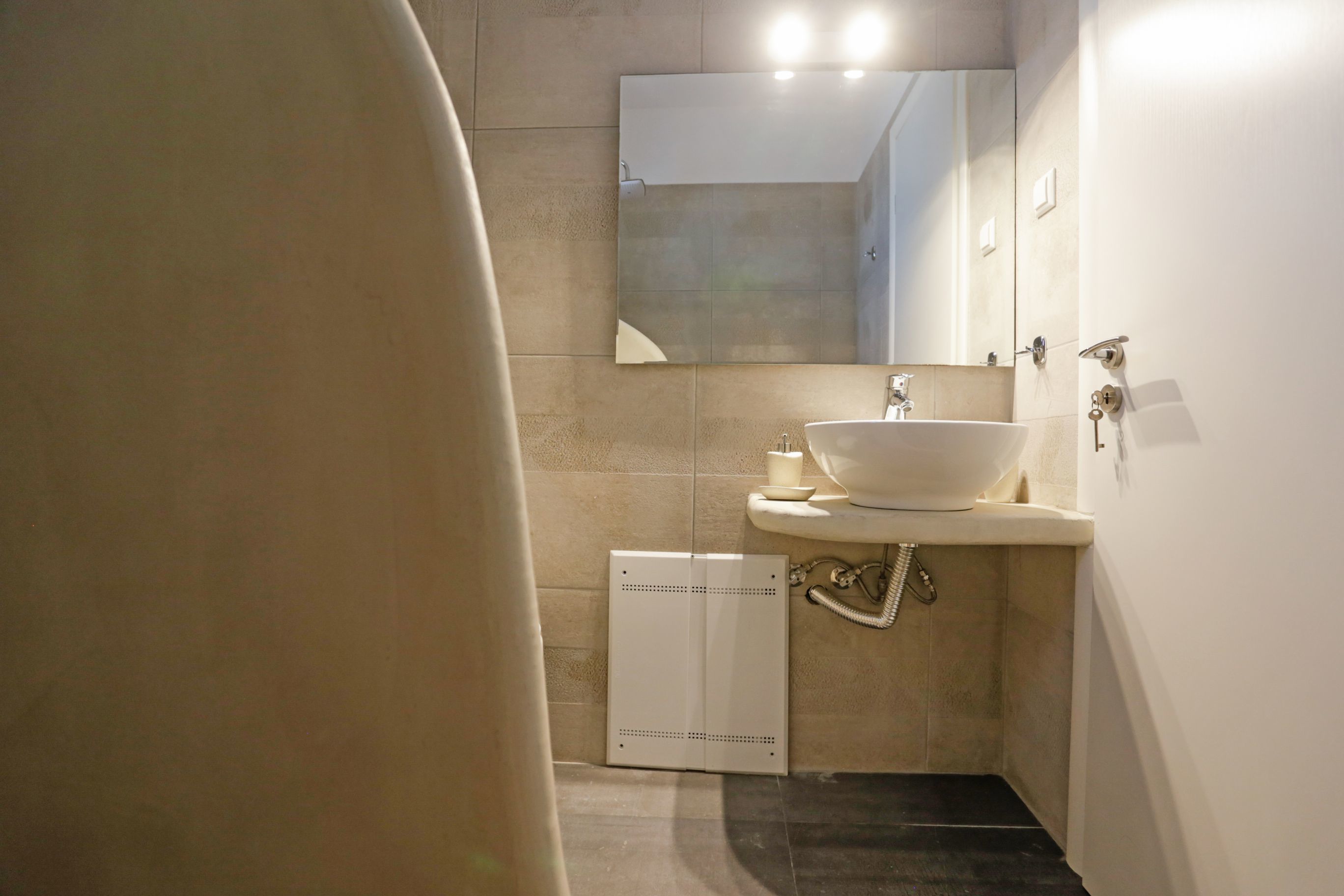 A modern bathroom with a white sink, a mirror above it, and a shower area.