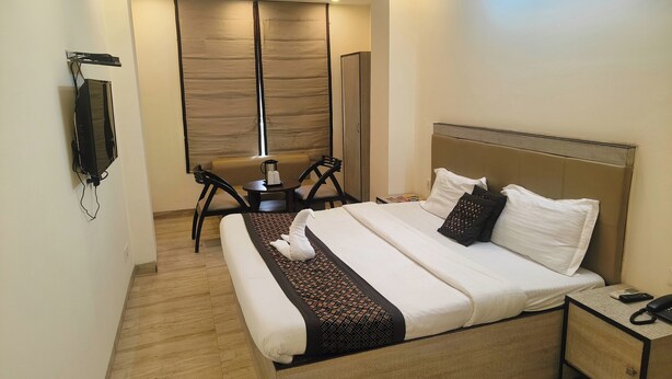 A modern hotel room with a large bed, a desk, a chair, and a TV mounted on the wall. - Hotel Grace at Karol Bagh (New Delhi)