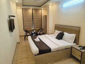 A modern hotel room with a large bed, a desk, a chair, and a TV mounted on the wall. - Hotel Grace at Karol Bagh (New Delhi)