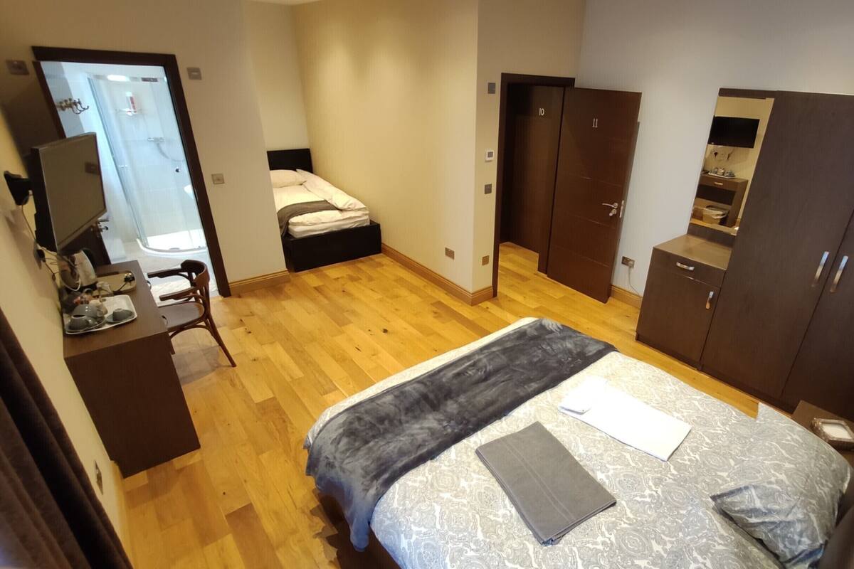 A bedroom with a bed, a desk with a chair, a wardrobe, and a mirror.