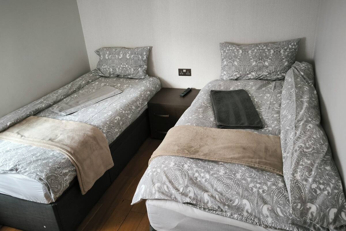 A twin room with two single beds, each with patterned bedding and a bedside table.