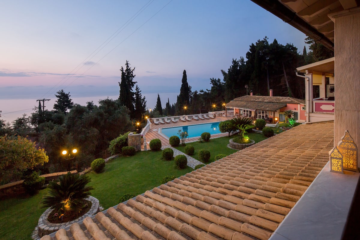 A villa with a swimming pool, terraced garden, and a view of the sea.