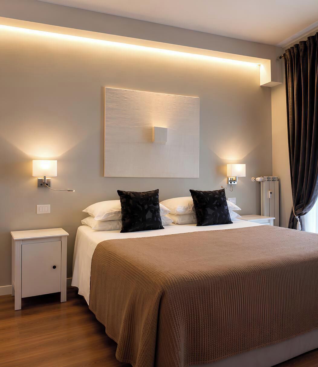 A hotel room with a bed, bedside lamps, a nightstand, and a large window with curtains.