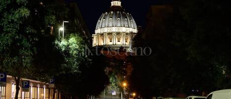 A street leading to a large, illuminated dome structure at night.