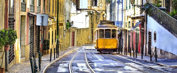 Un tranvía amarillo en una calle estrecha flanqueada por edificios.
