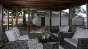 A covered patio with wicker furniture and a patterned rug.
