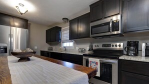 A modern kitchen with dark cabinets, stainless steel appliances, and a wooden countertop.