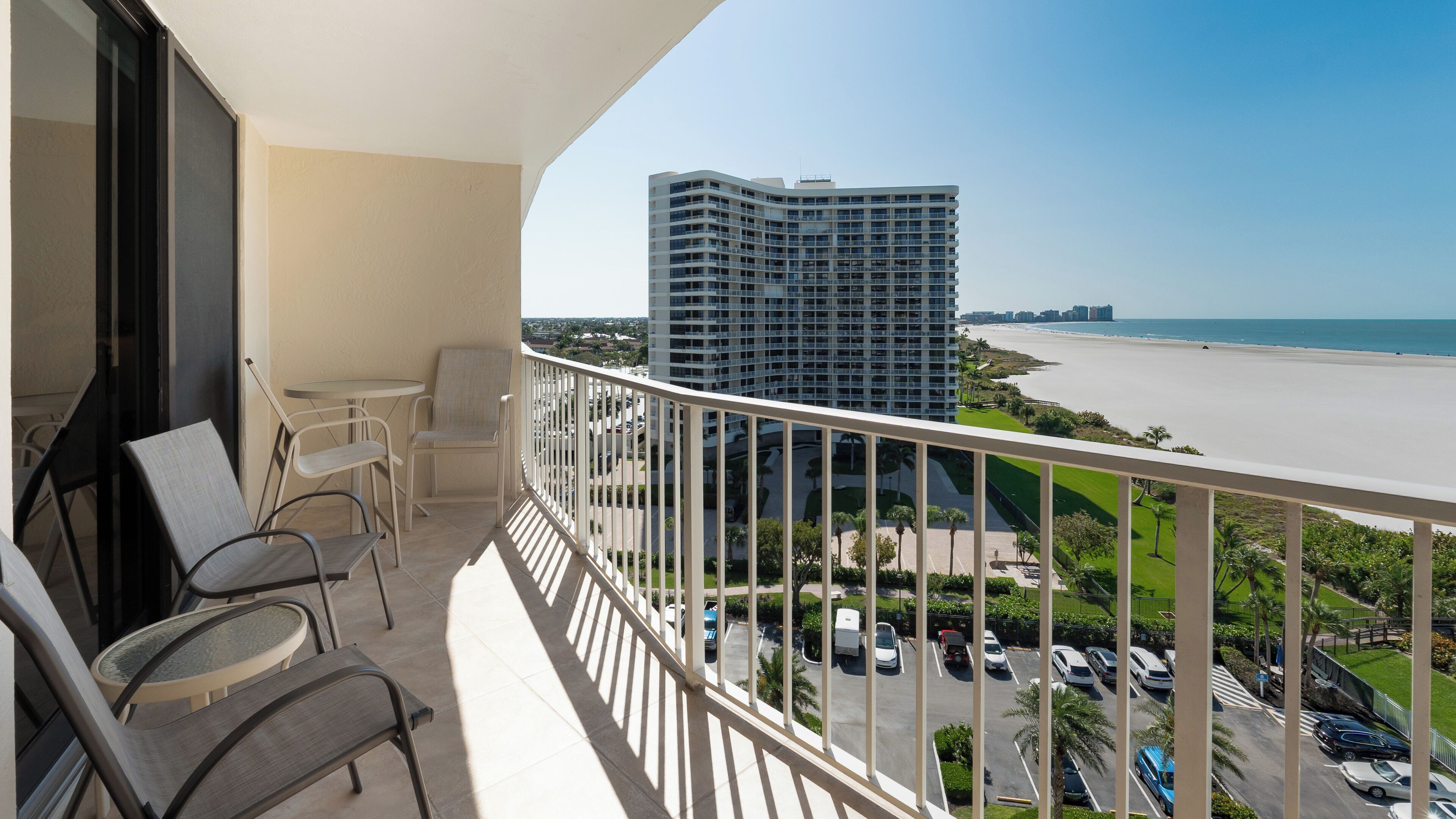 Een balkon met uitzicht op een strand en een hoog gebouw.