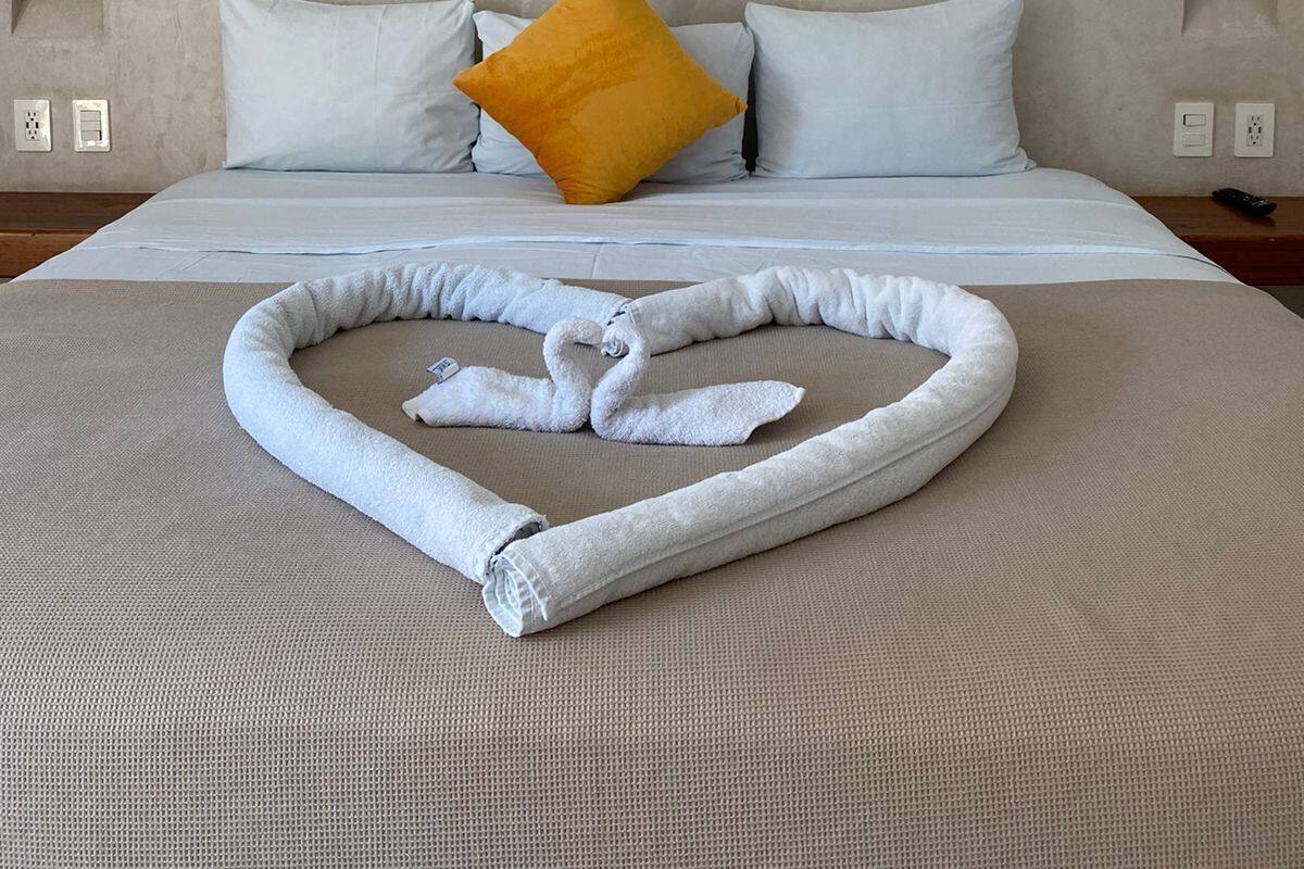 Habitación de hotel con cama, aire acondicionado de pared, una almohada amarilla y una toalla sobre la cama.