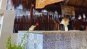 A thatched roof structure with a wooden sign reading "Delcans Suite". - Hotel Pelecanus Suites (Isla Holbox)