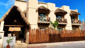 A hotel with a thatched roof, balconies with wooden railings, and a sign indicating it is a 'Deluxe Suite'. - Hotel Pelecanus Suites (Isla Holbox)