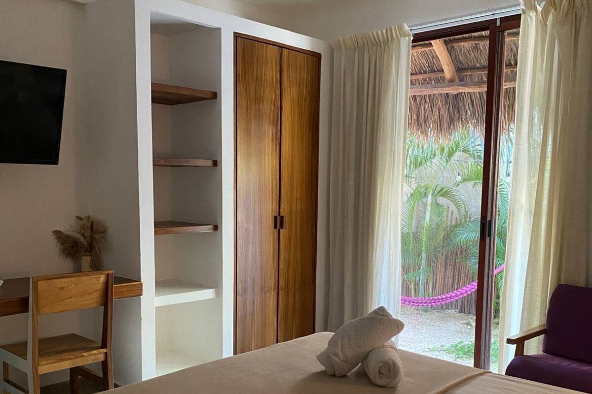 Una habitación de hotel con una cama, un armario de madera, un escritorio y una silla.
