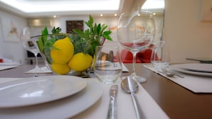 A dining table set with white plates, silverware, and clear glassware. A bowl with lemons and green leaves is also visible. - Athens Urban Visions Art Apartment. Breath taking Views to Acropolis.  (Athina)
