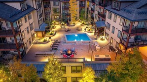 Un edificio residencial de varios pisos con un patio central que cuenta con una piscina, asientos al aire libre y una chimenea.