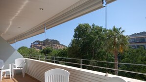 A balcony with white chairs and a table, overlooking a scenic view of a hill with buildings and trees. - EXCELLENT APARTMENT NEXT BEACH (Tossa de Mar)