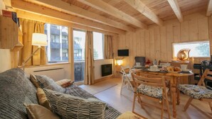 Un intérieur en bois comprenant un canapé, une table à manger, des chaises, un téléviseur et une cheminée.