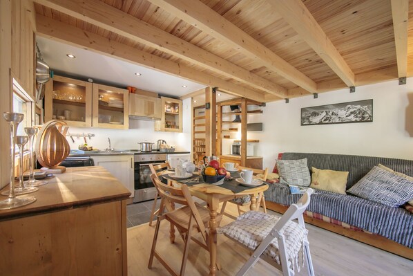 Een gezellige keuken met houten kasten, een eettafel met stoelen en een bank in de woonkamer.
