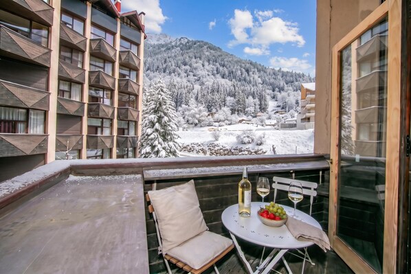 A balcony with a table set for two, overlooking a snowy mountain landscape. - Grand Roc C121 280m from Slopes, Parking & WiFi, Argentière (Chamonix), France (Argentière (Chamonix))