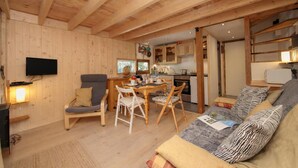 L’intérieur d’un chalet en bois chaleureux et accueillant, comprenant un coin repas, une cuisine et un espace salon.