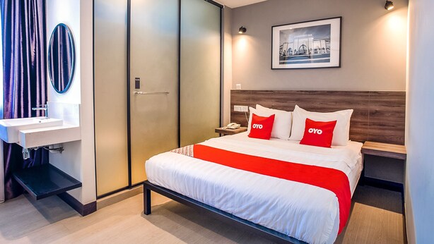 Una habitación de hotel moderna con una cama, una mesita de noche, un espejo, una puerta corredera y un cuadro en la pared.