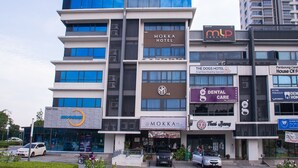 Un edificio de varios pisos que alberga diferentes comercios, como un hotel, una clínica dental y una cafetería.