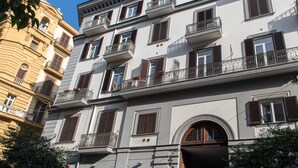 Un edificio de varios pisos con balcones, una tienda en la planta baja y cielo despejado.