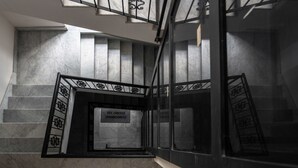 Una escalera con escalones de mármol y barandales de metal negro.