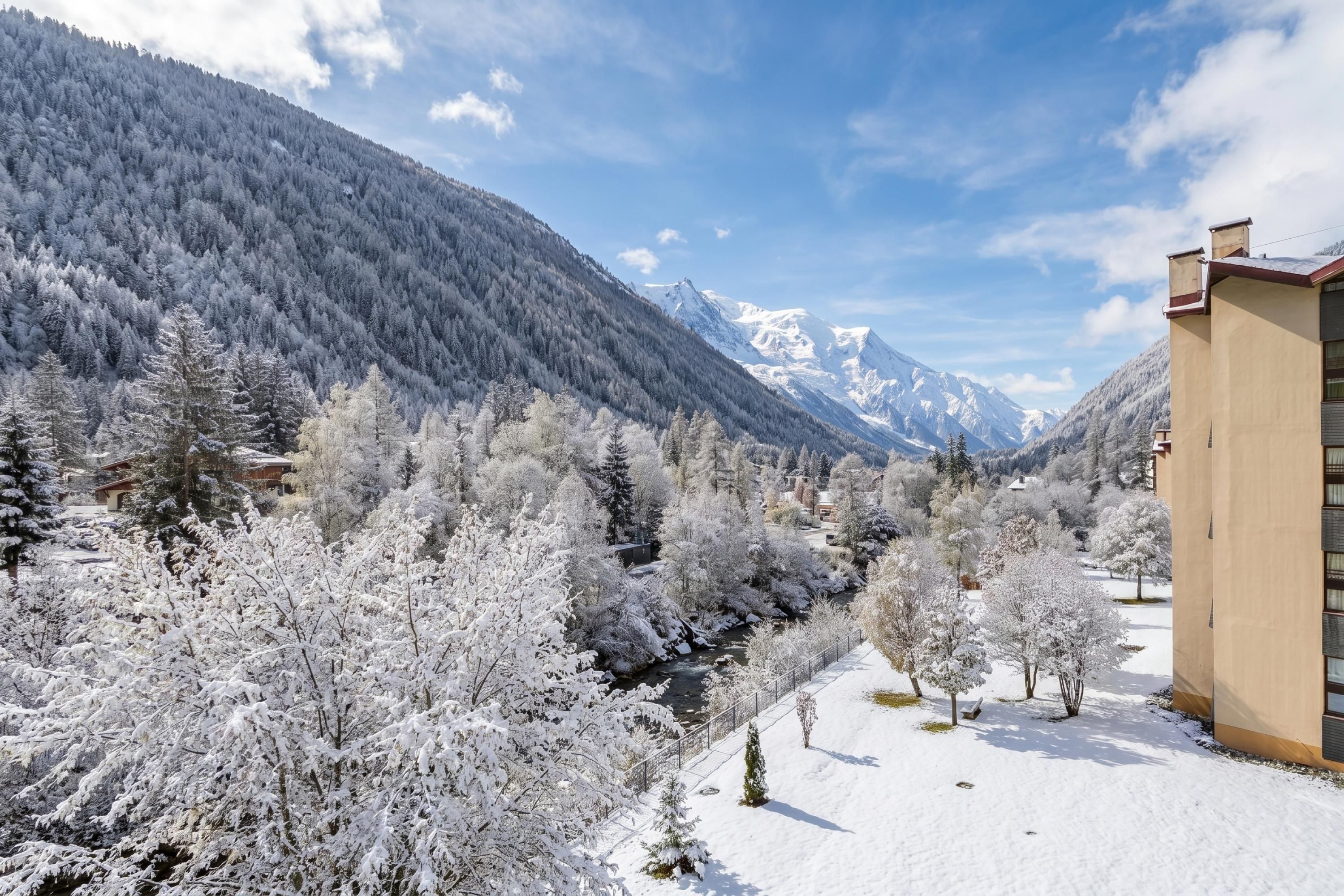 A snow-covered landscape with a mountain, a river, and a building with a flat roof.