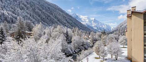 A snow-covered landscape with a mountain, a river, and a building with a flat roof.
