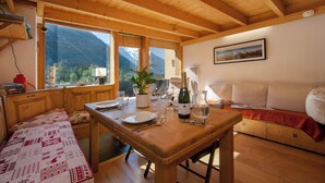 Interior em madeira com mesa de jantar, assentos e vista para a montanha.