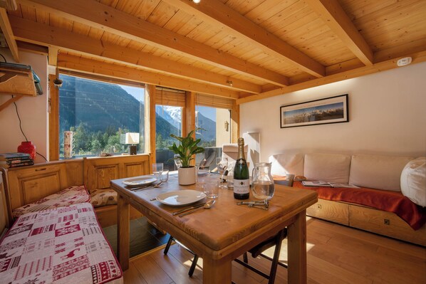 Un interior de madera con una mesa de comedor, asientos y vistas a la montaña.