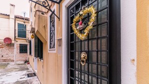 A building with a black metal gate, a gold wreath, and a lion head knocker.