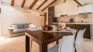 A modern kitchen with white cabinets, a dark countertop, and a dining area with a wooden table and white chairs.