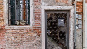 A brick building with a black metal gate and a window with decorative iron bars.