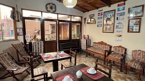 Un comedor con mesas y sillas de madera, una araña y adornos en las paredes, incluyendo banderas y cuadros enmarcados.