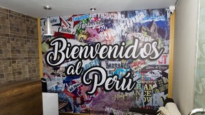 Una pared con un cartel que dice 'Bienvenidos al Perú' y varios adhesivos de colores.