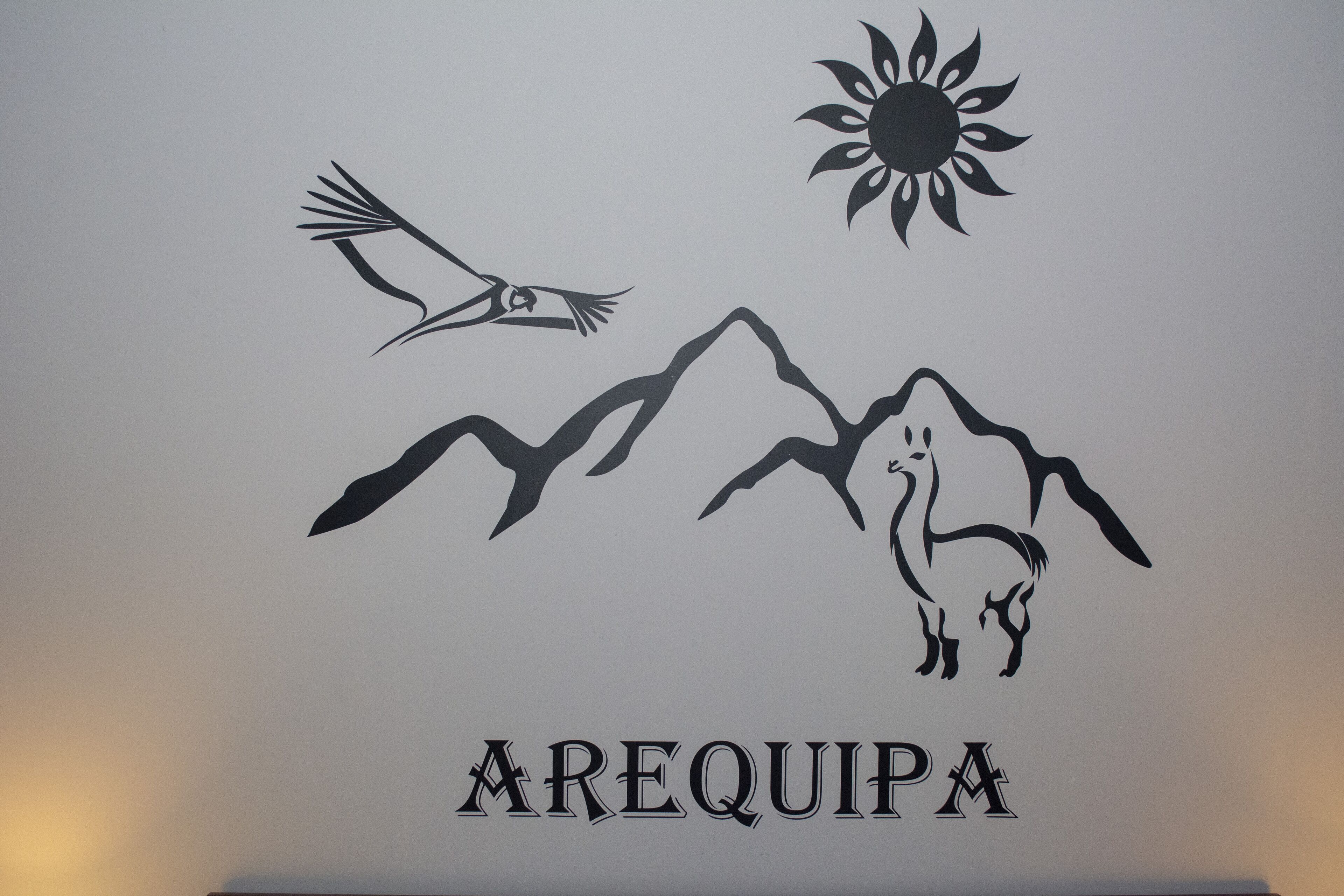 A wall decal with a bird, sun, and mountains, and the word "AREQUIPA".