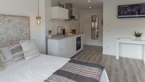 A modern bedroom with a large bed, a small kitchenette, and a TV mounted on the wall. - AMAZING STUDIO in the CENTER of TOSSA (Tossa de Mar)