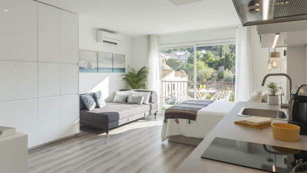 A modern apartment with a balcony, a kitchenette, and a large window offering a view of the city. - AMAZING STUDIO in the CENTER of TOSSA (Tossa de Mar)