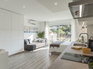 A modern apartment with a balcony, a kitchenette, and a large window offering a view of the city. - AMAZING STUDIO in the CENTER of TOSSA (Tossa de Mar)