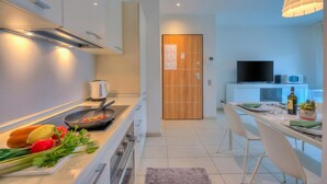 A modern kitchen with a stove, microwave, and dining area with chairs and a table. - Prestige du Lac 27 with Balcony and Parking, Lugano, Switzerland (Lugano)